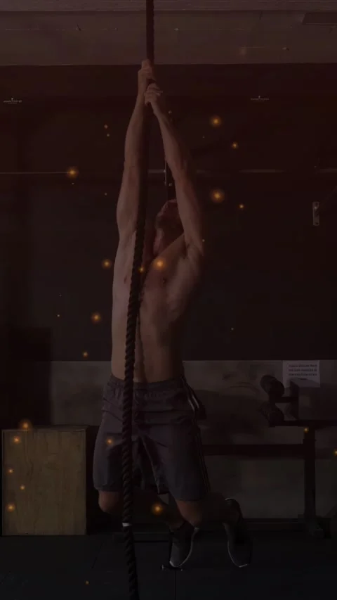 Vertical video: Man gripping rope climbing pulling leg lock for fitness, orange Stock Footage 333978091