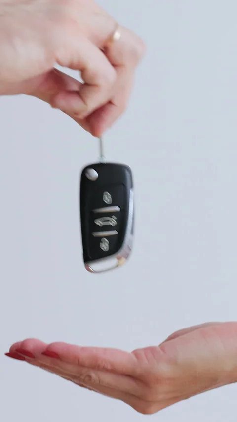 Vertical video. Man hand gives a car keys to woman hand in the car dealership Stock Footage 345703271