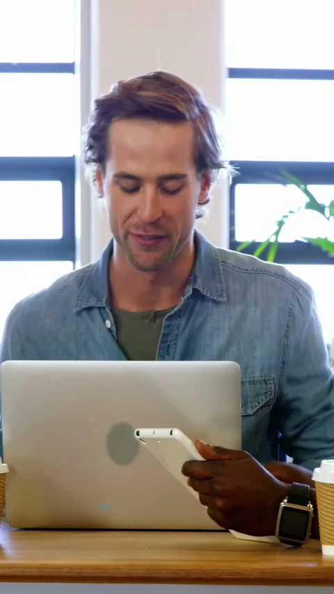 Vertical video: Man handing smartphone, colleague tapping laptop and reviewing Stock Footage 340133531