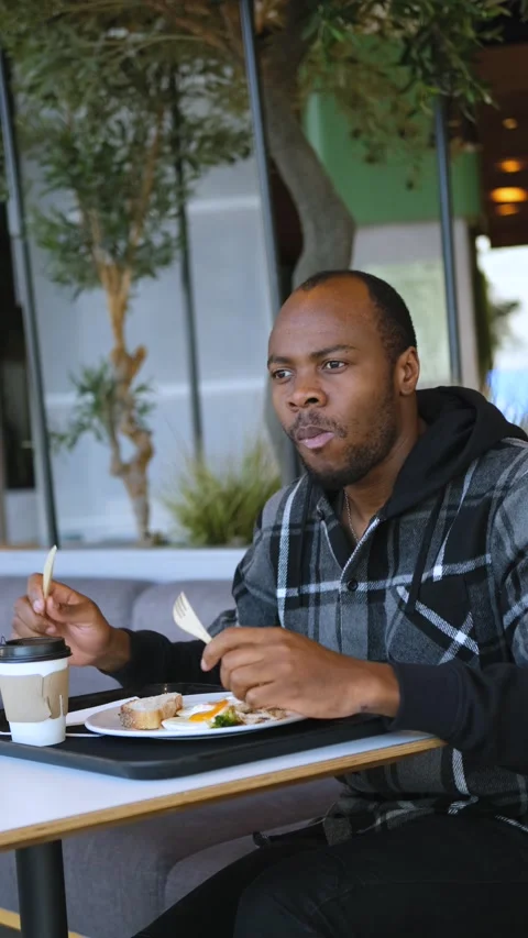 Vertical video of a man having breakfast in a cafe 動画素材 234548626