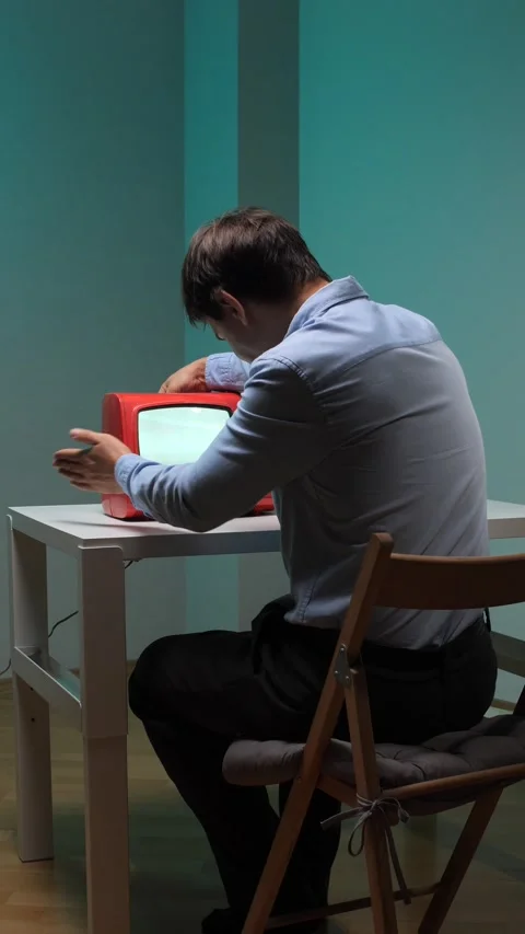 Vertical video man with head bowed, sitting at a table and interacting with a 動画素材 344605708
