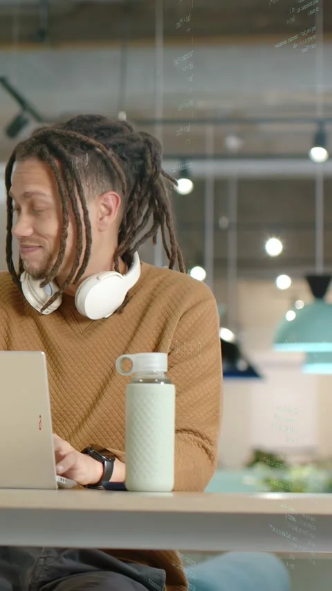 Vertical video: Man hearing offscreen cue, resuming coding on laptop with code Stock Footage 333596434