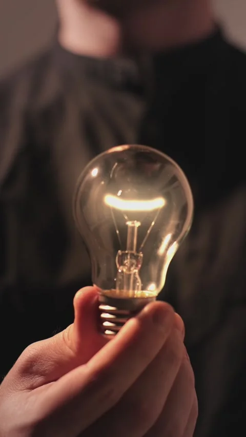 Vertical Video : Man holding a light bulb and it turns on, concept of idea Stock Footage 303525814