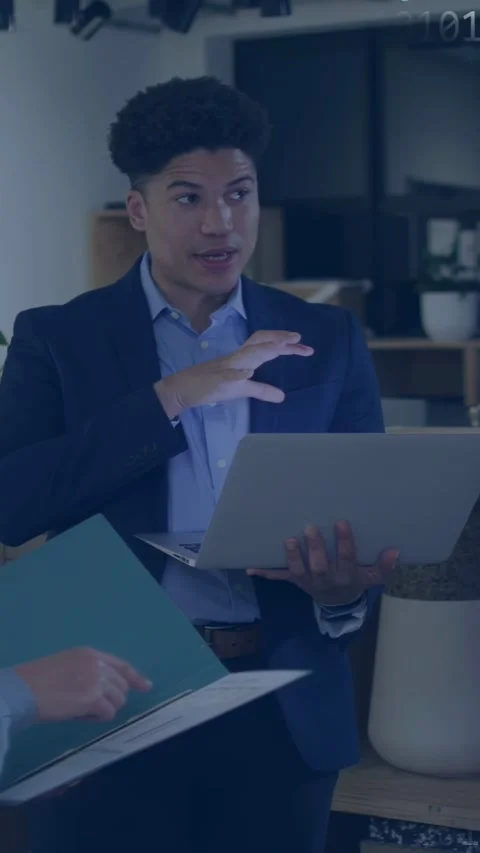 Vertical video: Man with laptop explaining tech while peer pointing papers Stock Footage 337540772