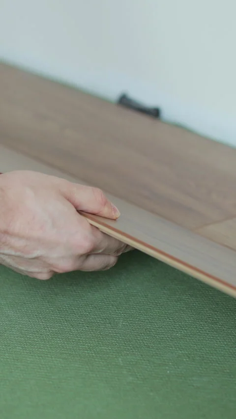 Vertical video Man lays laminate flooring on the floor in a room. 스톡 동영상 339060746