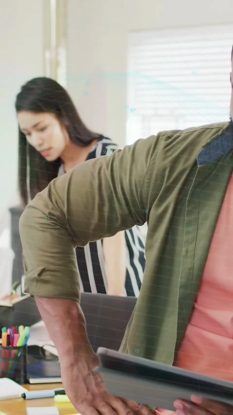 Vertical video: Man leaning on desk shifting pad, woman writing notes for Stock Footage 334128066