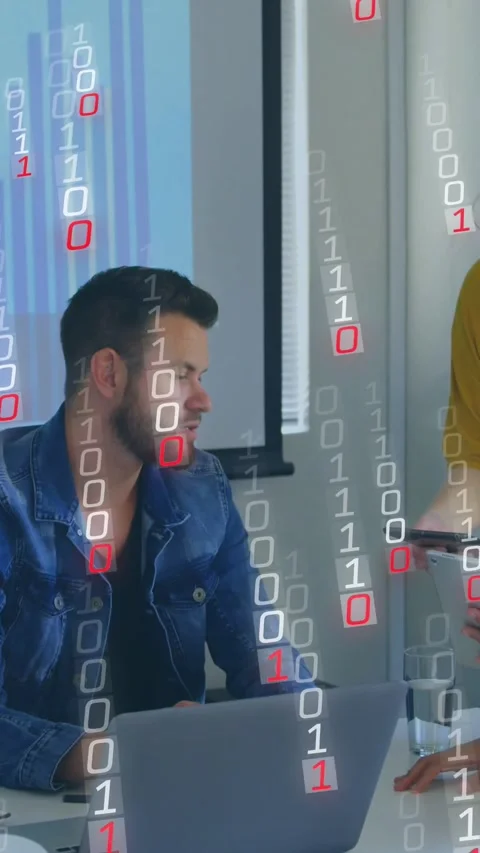 Vertical video: Man leaning at laptop woman placing tablet making 0s1s rain over Stock Footage 330195784