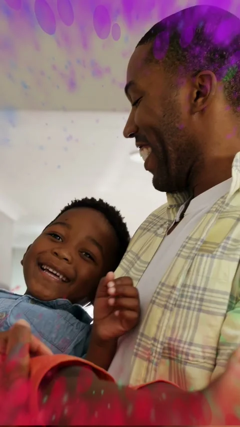 Vertical video: Man lifting child in home, sparking paint splatter around them Stock Footage 335513971