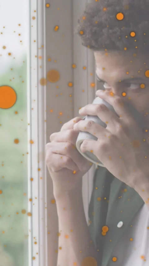 Vertical video: Man lifting mug, sipping, reflecting at window, orange haze, cam Stock Footage 328309091