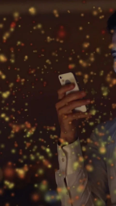 Vertical video: Man lifting phone, checking phone as tech particles drifting, Stock Footage 331215479