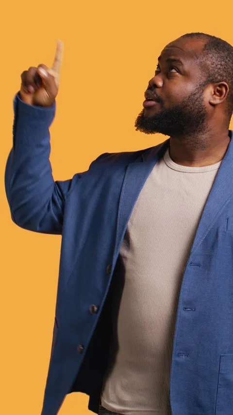 Vertical video Man looking up, showing something to audience, studio background Stock Footage 272709318