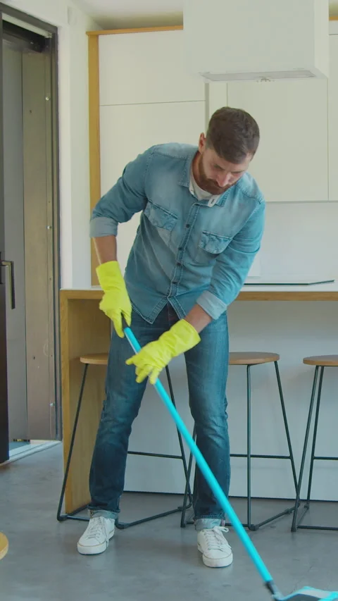 Vertical Video Man is mopping floor at home and having fun. Stock Footage 337994650