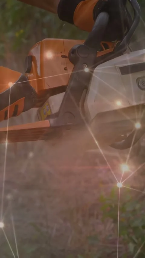 Vertical video: Man moving chainsaw to trunk, cutting for garden while sparkles Stock Footage 334391875