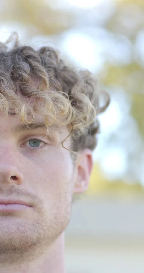Vertical video: Man opening eyes after blink, meeting camera gaze outdoors with Stock Footage 346718896