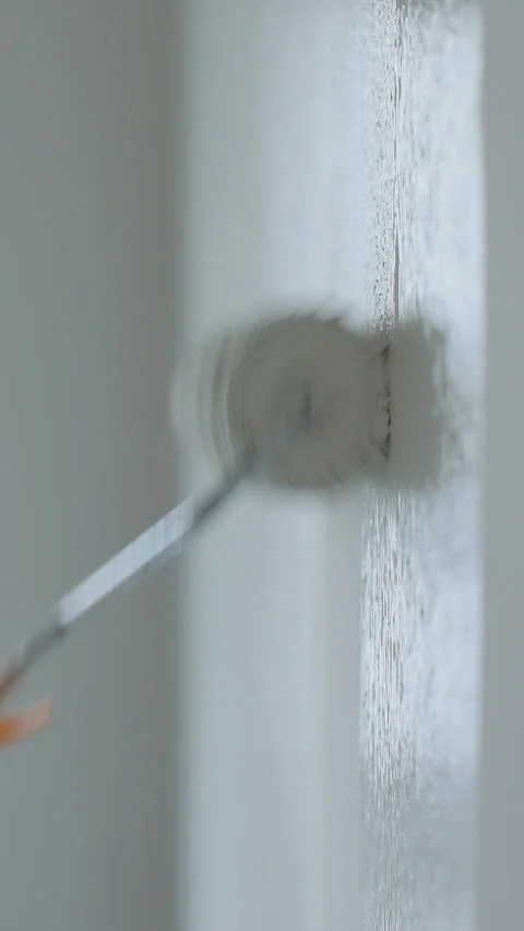 Vertical video Man painter painting a house wall with a white paint roller. Stock Footage 339059881