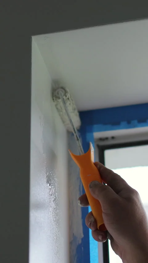 Vertical video Man paints the wall with a roller with white paint. Stock Footage 339059993