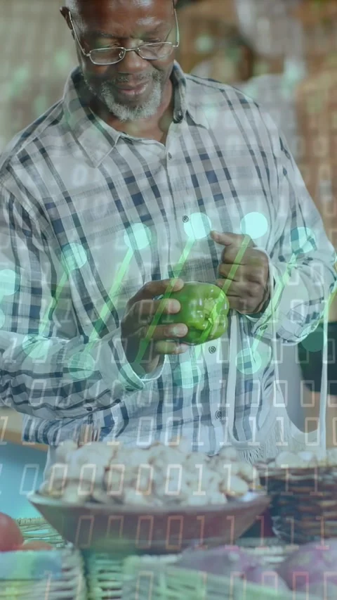 Vertical video: Man picking, turning pepper in market while binary overlay Stock Footage 333912945