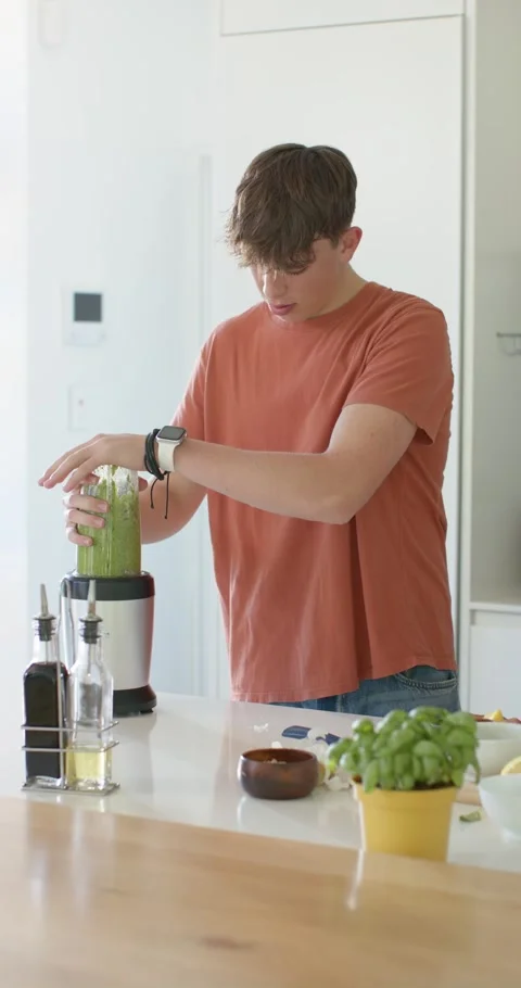 Vertical video: Man is placing and securing jar on blender base to blend green Video stock 345321874