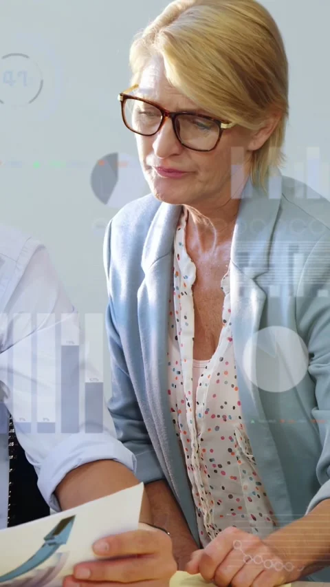Vertical video: Man placing chart, senior woman leaning in examining chart for Stock Footage 332735018