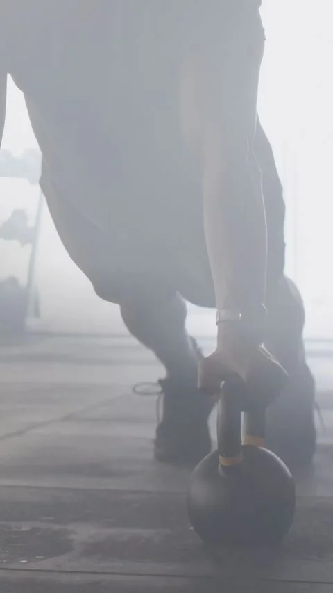 Vertical video: Man placing hands on kettlebells, performing push-ups to build Video stock 333304696