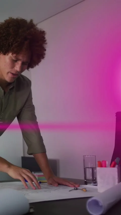 Vertical video: Man placing hands on plans, reviewing layout for design, magenta Stock Footage 333496220