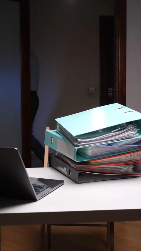 Vertical video Man placing stack of colorful binders on office desk Stock Footage 322912012