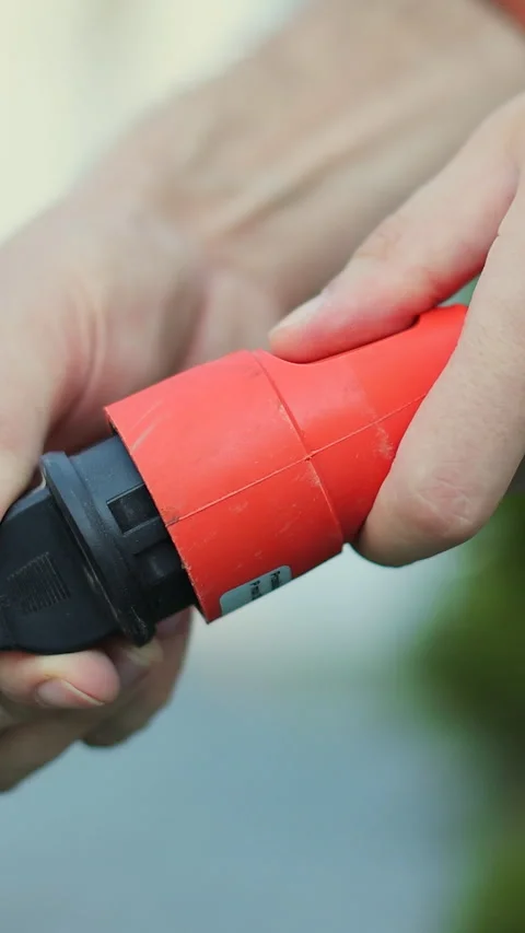 Vertical video Man plugs in an electric lawnmower. Stock Footage 339062017
