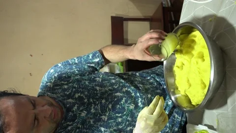 Vertical video of a man pouring lemon juice and kneading yellow potato with his 스톡 동영상 171945793