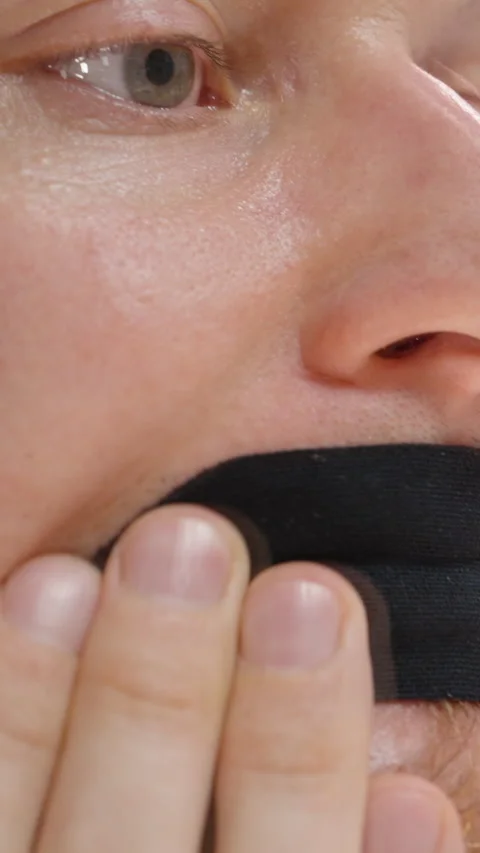 Vertical video. Man Pressing Black Mouth Tape onto Lips with Both Hands in Stock Footage 306019879