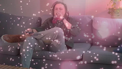 Vertical video: Man pressing remote, surfing TV, sipping bottle on couch, pink Stock Footage 333318216