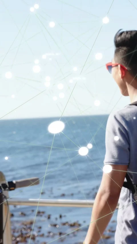Vertical video: Man at railing gazing ocean, gaze sparking animated tech node Stock Footage 333954074