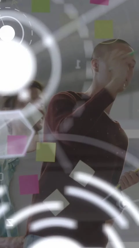Vertical video: Man raising marker, annotating glass, colleague checking tablet, 库存影片 334046815