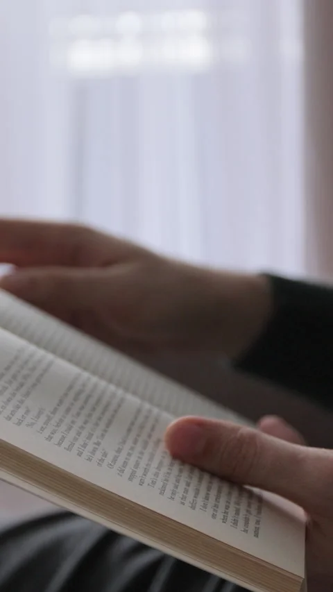 Vertical video. Man reading a book, close up. Hands flipping through pages. Stock Footage 343763778
