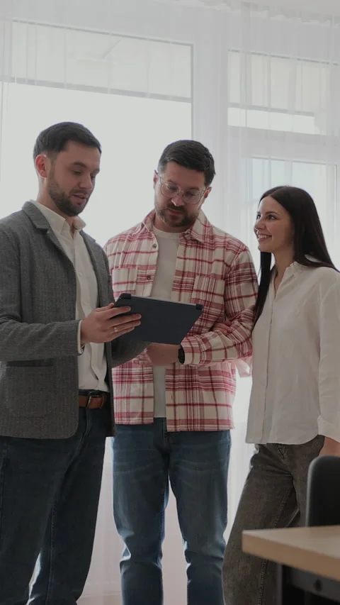 Vertical video Man real estate agent showing young couple apartment plan Stock Footage 340082437