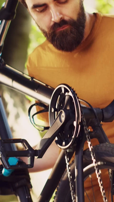 Vertical video Man realigning bicycle pedals in yard Stock Footage 247495444