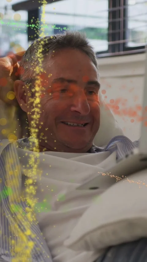 Vertical video: Man relaxing on sofa tapping tablet and creating tech particles Stock Footage 333496504