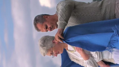 Vertical video. A man of retirement age approached an older woman and covered Video stock 258912853