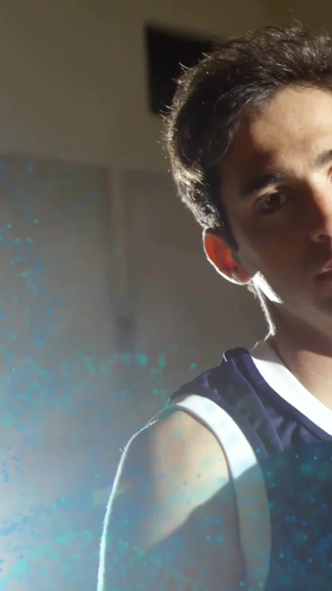 Vertical video: Man rotating to camera set, teal dust drifting over face causing Vidéo 331790064