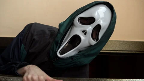 Vertical video a man in a screaming mask appears from the doorway. A maniac in a Stock-Footage 163778472