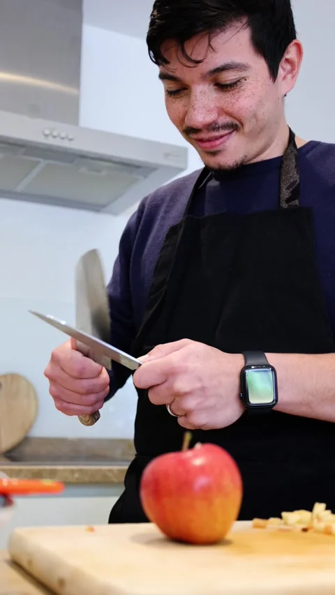 Vertical video of man sharpening knives to cut some apples on a wooden boar.. Stock Footage 297371076