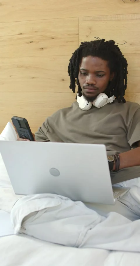 Vertical video: Man shifting gaze between phone and laptop, responding to Stock Footage 345323712