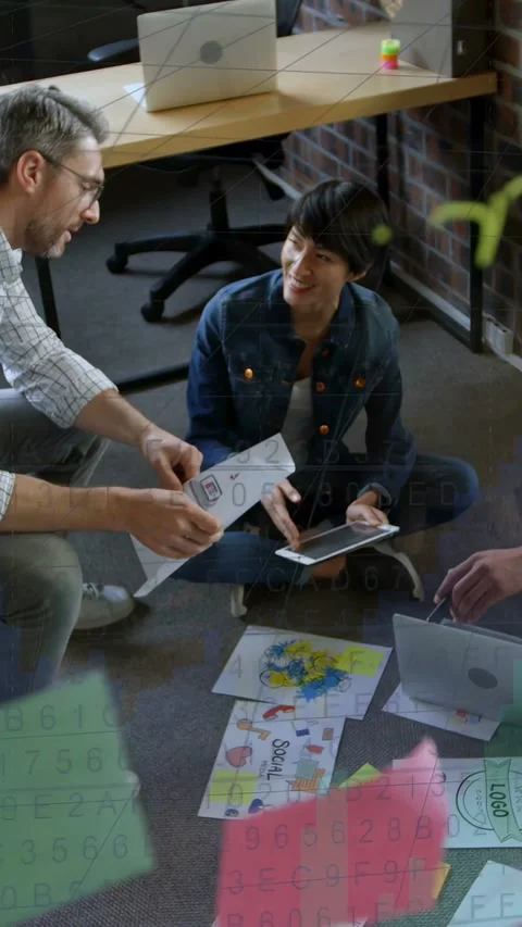 Vertical video: Man showing mockup, woman tapping tablet, team reviewing design Stock Footage 333465191