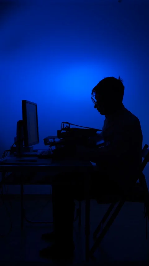 Vertical video Man silhouette working on computer with blue light Stock Footage 318979669