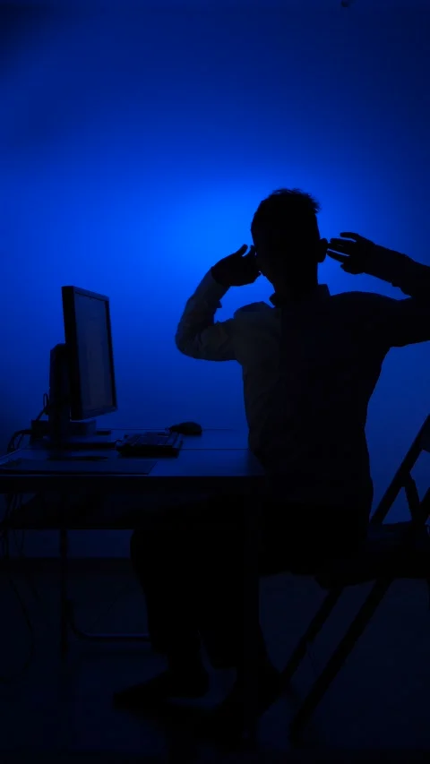 Vertical video Man silhouette working late on computer experiencing blue light Stock Footage 322911633