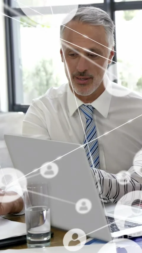 Vertical video: Man sitting at business desk while peer tapping PC making icons Stock Footage 334317801
