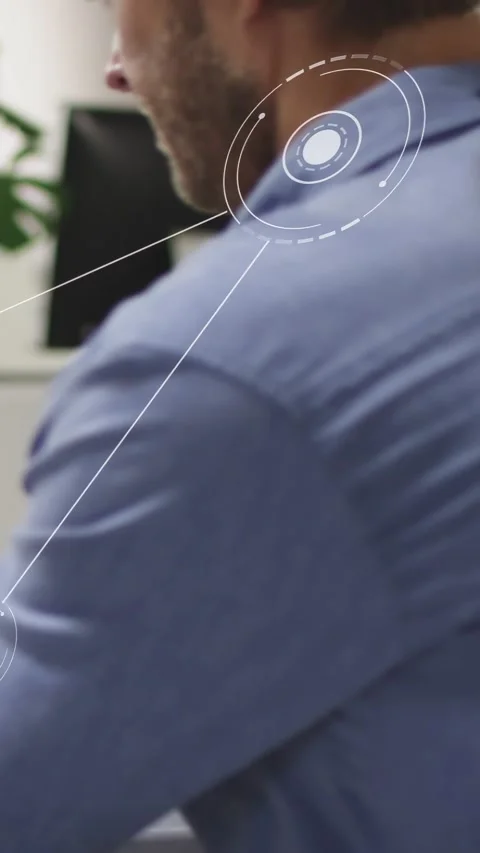 Vertical video: Man sitting at desk while HUD animating, lines forming triad Stock Footage 333110098