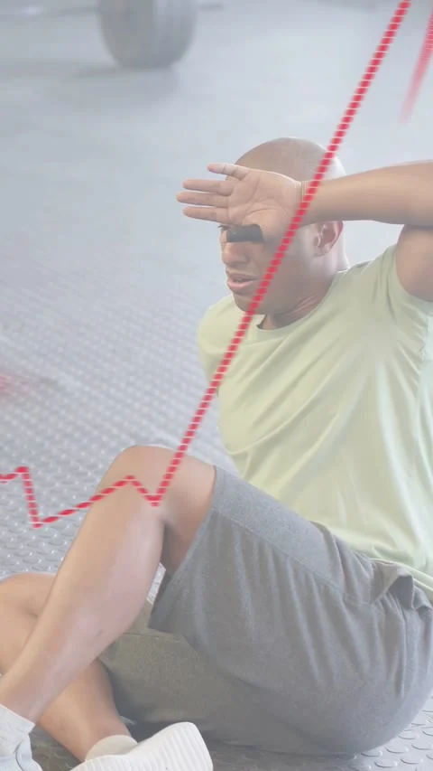 Vertical video: Man sitting up on gym floor after set, red animated arrow rising Stock Footage 333821010