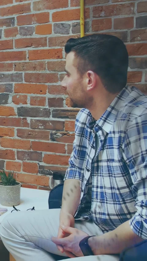 Vertical video: Man sitting in office responding to left speaker, turning, Stock Footage 334549859