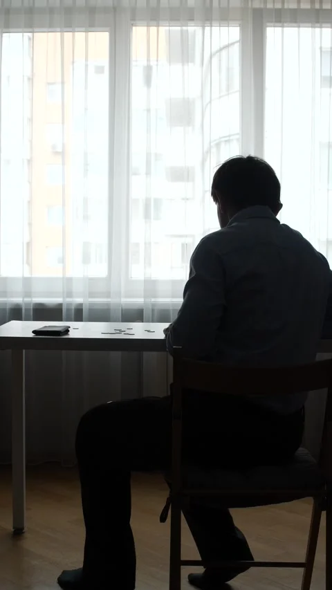 Vertical video man sitting at a table with coins, looking into an empty wallet Stock Footage 346251284
