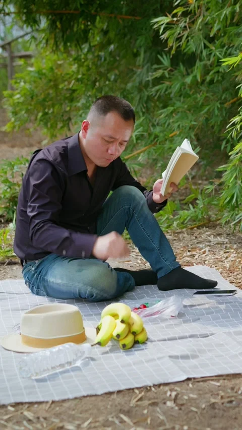 Vertical Video man soaks up the sun in bamboo forest for the weekend. 스톡 동영상 331281725